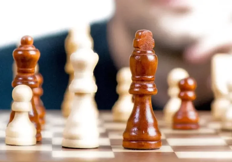 A man is playing chess on a chess board.