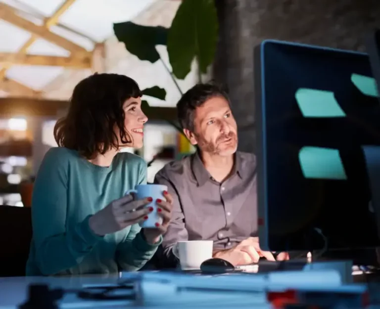 A man and woman are looking at a computer screen.