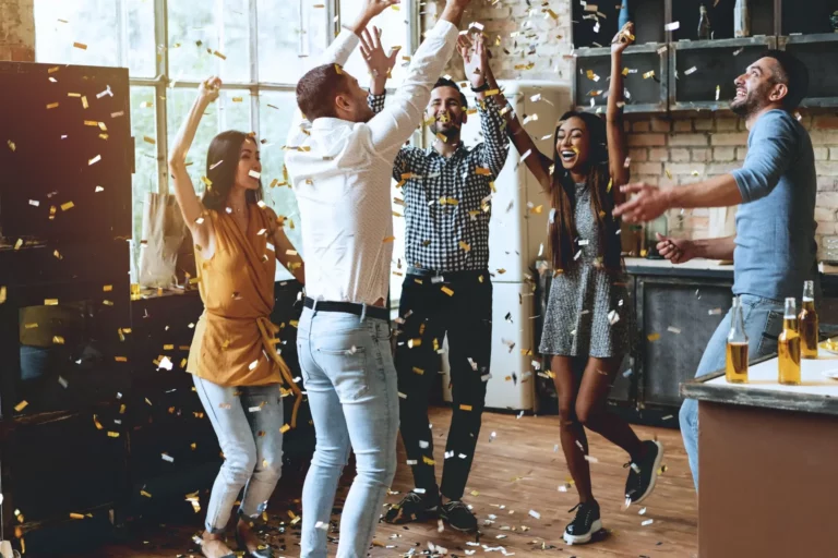 A group of people celebrating in a kitchen with confetti.
