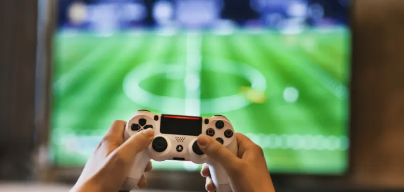 A person holding a video game controller in front of a television.
