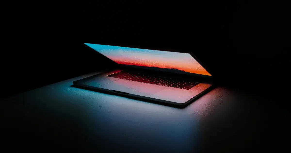 A laptop with a colorful screen in the dark.