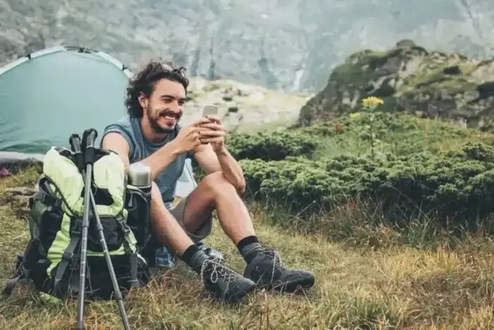 A man sitting in grass with a phone.