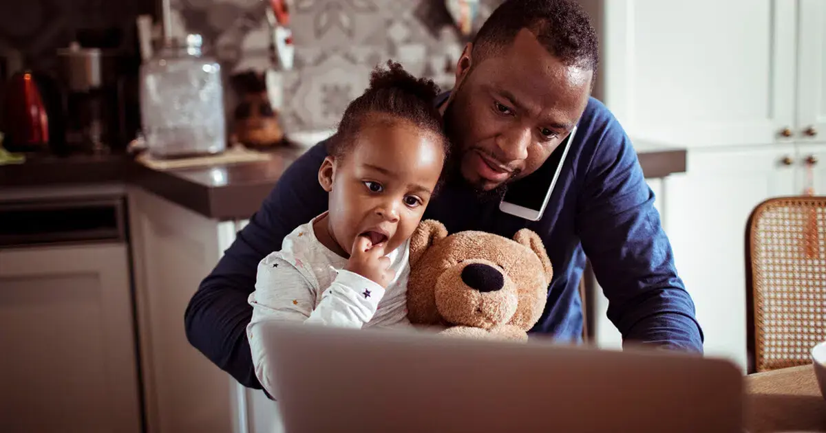 A man with a teddy bear and a child using a laptop.