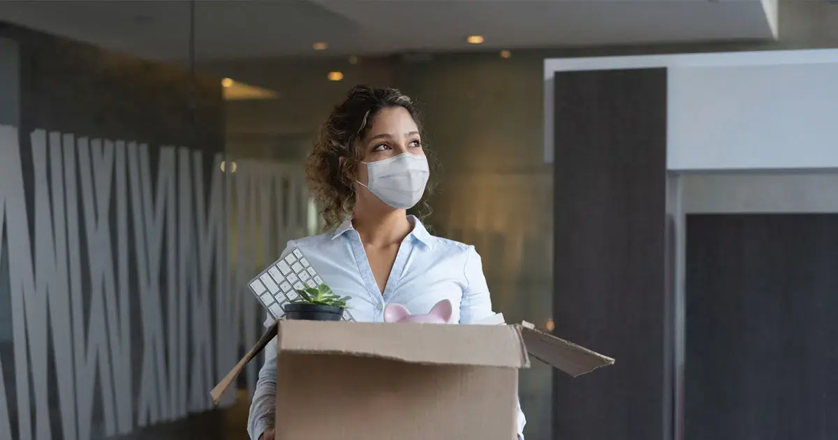 A woman wearing a face mask and carrying a box.