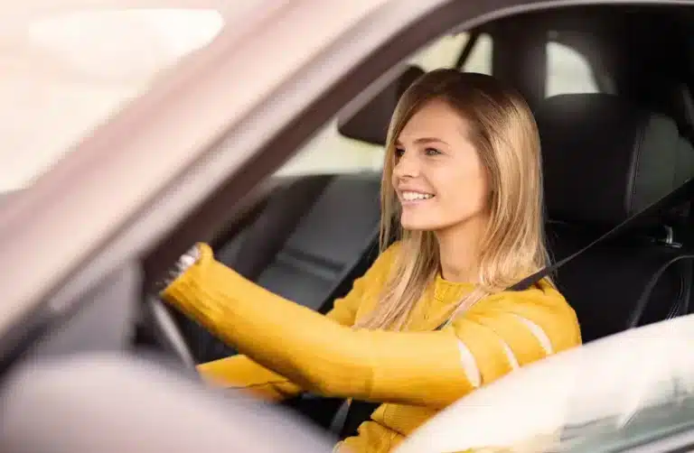 A young woman is driving a car.