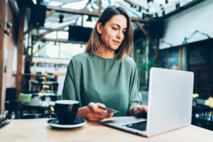 A woman sitting at a table with a laptop and a cup of coffee.