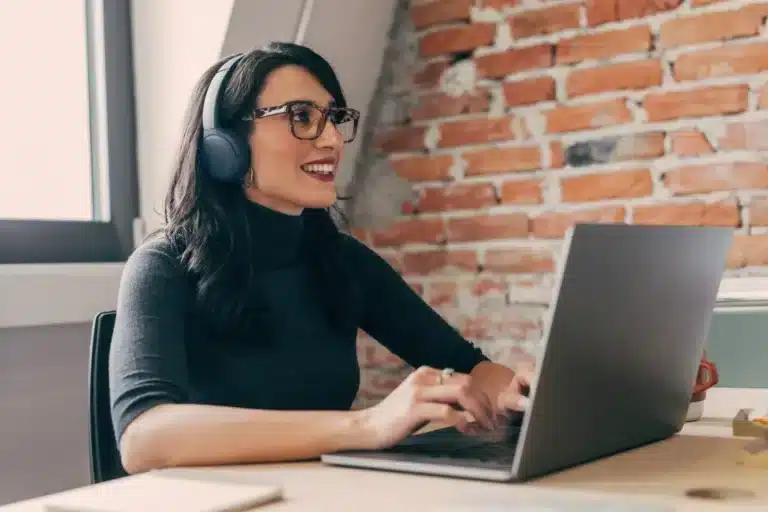 A woman wearing headphones is working on a laptop.