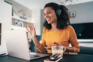 A woman wearing headphones is working on her laptop at home.