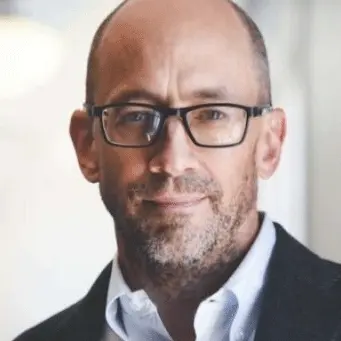 A bald man wearing glasses and a jacket.