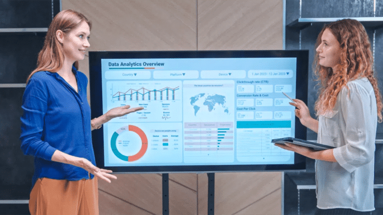 Two women standing in front of a board with graphs on it.