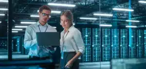 Two people in a data center looking at a laptop.
