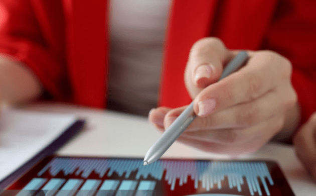 A person holding a stylus, poised above a touchscreen displaying bar and line graphs, suggests seamless synergy in digital interaction and data analysis from the comfort of home.