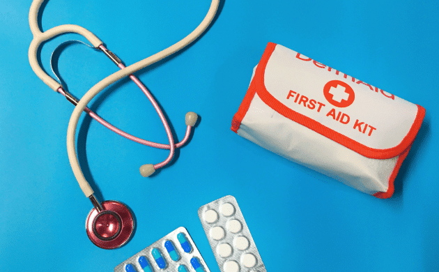 A stethoscope, a first aid kit, and blister packs of pills are arranged on a blue surface, creating a perfect synergy of healthcare essentials for any home.