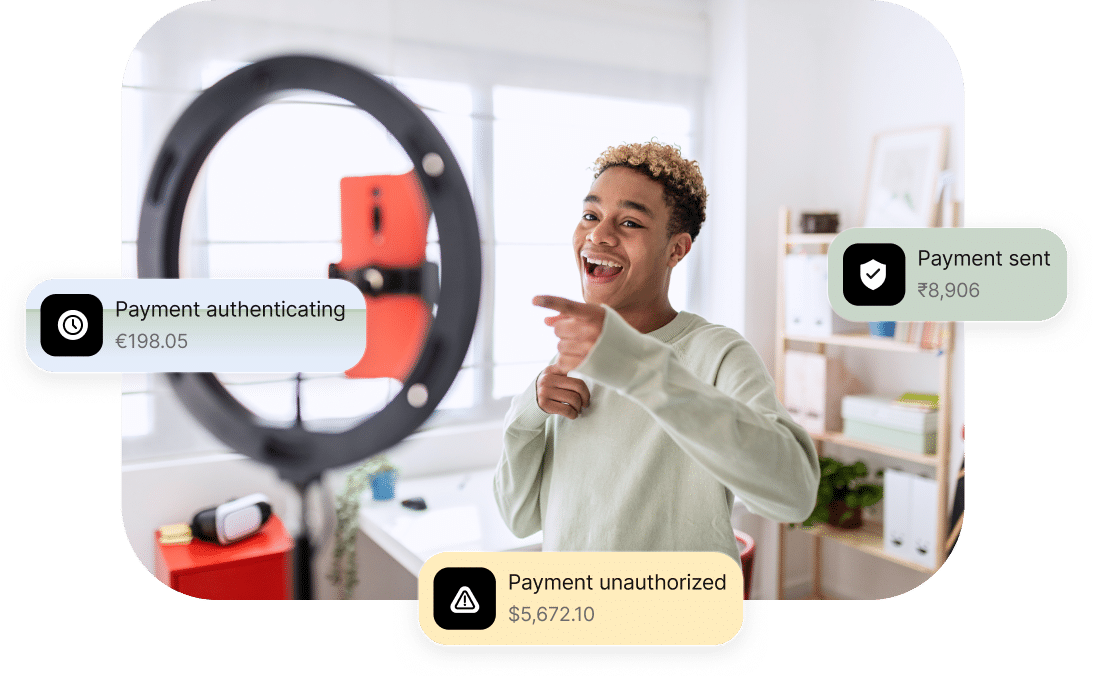 A person smiling and pointing in front of a ring light with a phone. Three floating notifications show payment statuses: "Payment authenticating," "Payment sent," and "Payment unauthorized.