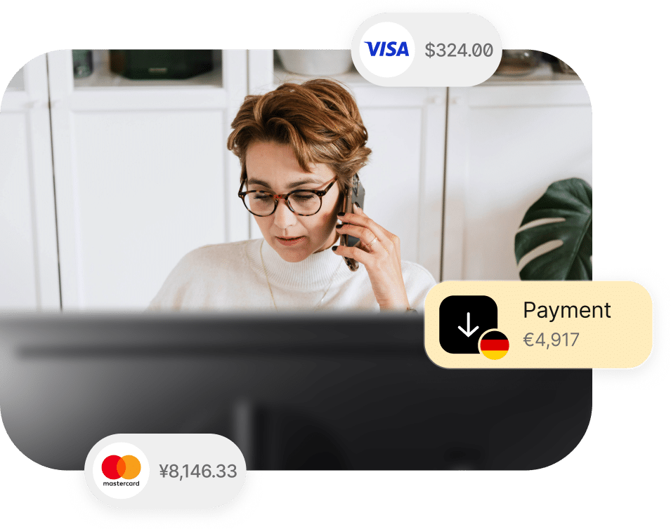 A person on the phone is sitting in front of a computer. Surrounding the image are icons showing payment amounts: VISA with $324.00, Mastercard with ¥8,146.33, and a download icon for €4,917.