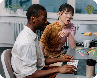 Two people sit at a desk in a modern workspace, collaborating on a computer as they explore ai solutions, with office supplies and mugs nearby.